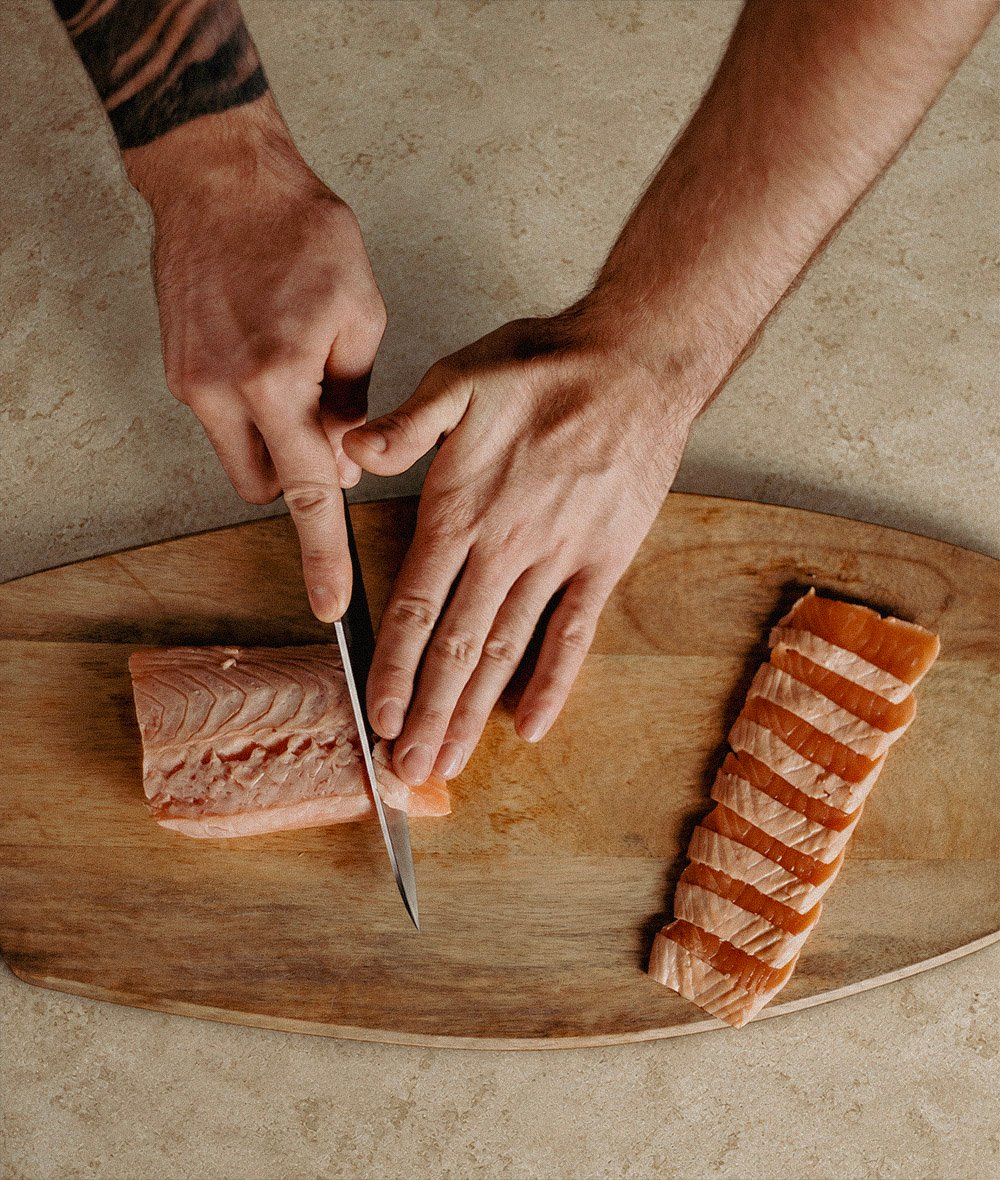 Widok z góry na ceramiczny talerz z plastrami sashimi hamachi, ogórkiem i shiso w promieniach słońca